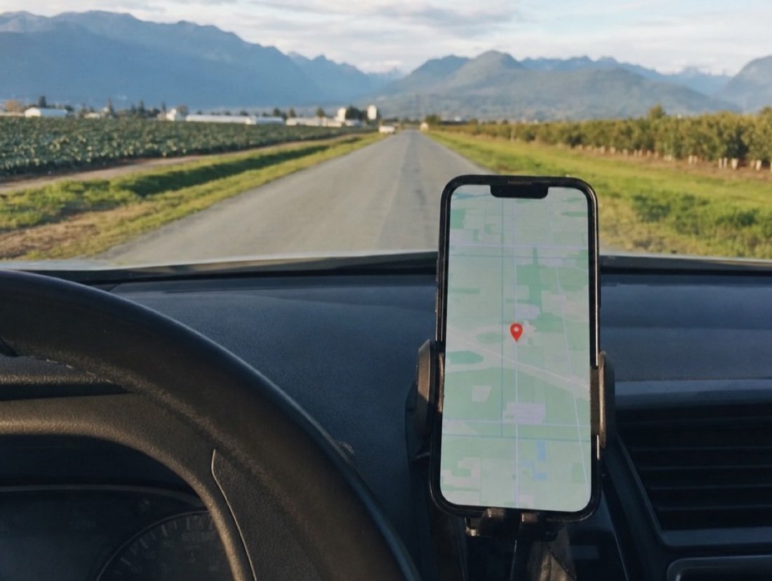 Navigation on a phone fixed to the dashboard, the route ending at a pin past open farmland